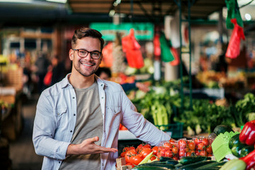 Portrait of a farmer man presenting a vegetable stall at local market.