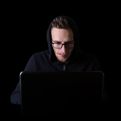 Hacker,programmer on glases in front of his computer, with laptop initiating cyber attack, isolated on black backgroung
