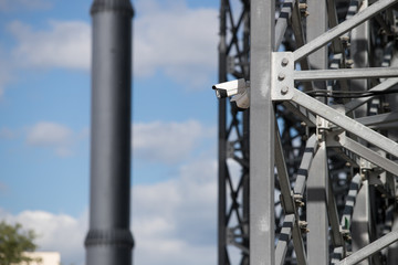 View of a contemporary surveillance video cam attached to a metal girder of the facade of a modern business skyscraper; security video camera on the frontage of an office high-rise 