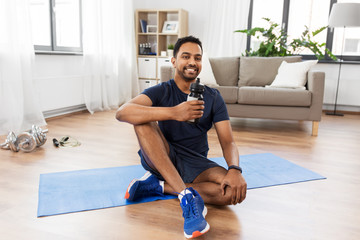 Naklejka premium fitness, sport and healthy lifestyle concept - smiling indian man drinking water after training at home