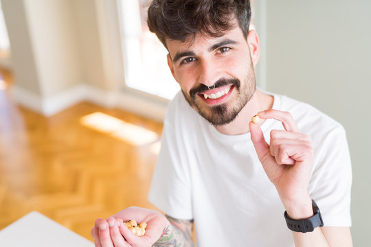 Young man eating hazelnuts, close up of hand with a bunch of healthy nuts