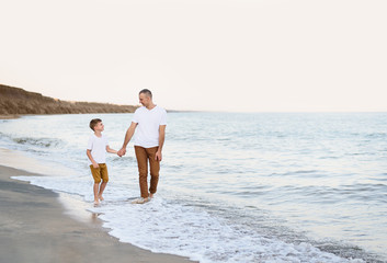 Father and son go by the hand along the sea coast. Family vacation. Friendship