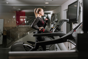Fototapeta na wymiar Fit woman running on treadmill in the gym