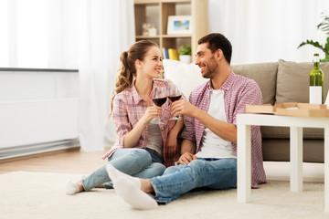 Naklejka na ściany i meble leisure, celebration and valentines day concept - happy couple drinking red wine at home