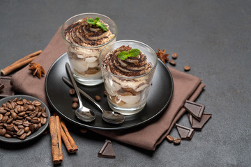 Classic tiramisu dessert in a glass on dark concrete background