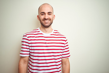 Young bald man with beard wearing casual striped red t-shirt over white isolated background with a...