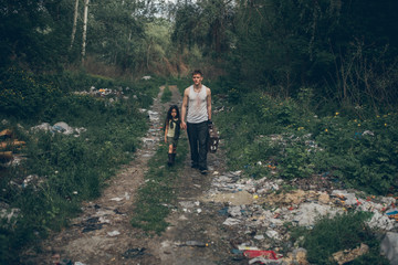 Obraz premium Homeless father and daughter walk through the garbage dump.