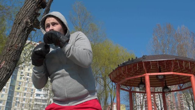 Boxer in boxing gloves training outdoors, shadow boxing
