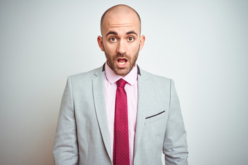 Young business man wearing suit and purple tie over isolated background afraid and shocked with surprise expression, fear and excited face.