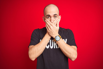 Young safeguard man wearing security uniform over red isolated background shocked covering mouth with hands for mistake. Secret concept.