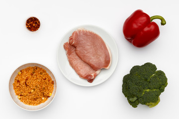 Raw ingredients for a bowl of a delicious Jerk Pork and couscous with vegetables and spices.