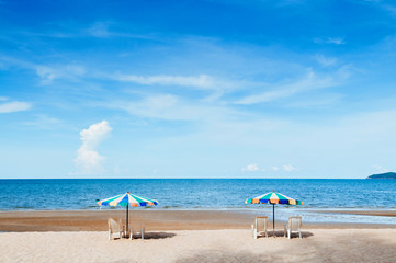 Beach beds and colourful umbrellas with ocean horizon view and clear sky slightly clouds in summer