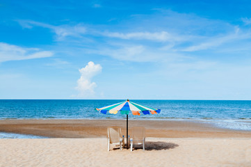 Obraz na płótnie Canvas Beach beds and colourful umbrella with ocean horizon view and clear sky slightly clouds in summer