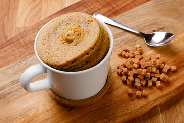 Delicious fudge sponge pudding shot on a wooden board with a hand full of fudge pieces.