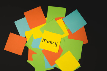 the word money on a piece of yellow paper among multicolored paper
