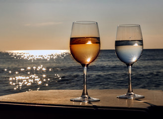 Two glasses of wine at sunset by sea