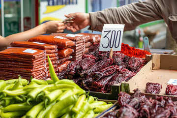 Different types of green and red peppers on the marketplace in Belgrade. Blurred background of seller and customer hands paying cash