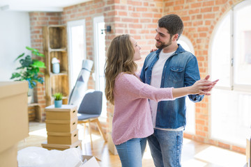 Young couple dancing celebrating moving to new apartment around cardboard boxes