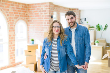 Young couple around cardboard boxes very happy moving to a new home