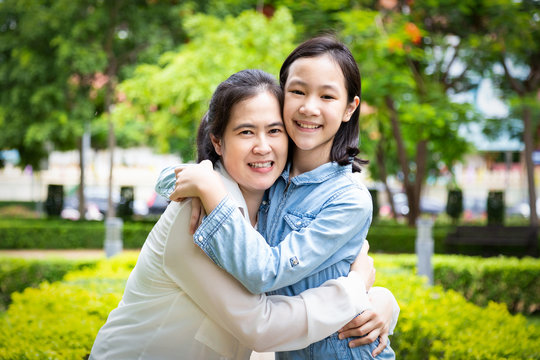 Happy beautiful asian adult woman and cute child girl hugging and smiling in garden,love of mother with her little daughter in outdoor park in nature,mother’s day, family, love concept