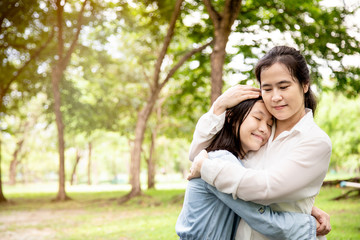 Naklejka premium Happy beautiful asian adult woman and cute child girl with hugging and smiling in summer,love of mother with her little daughter in outdoor park in nature,mother’s day, family, love concept