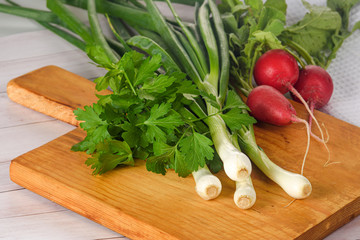 green onions, parsley and radish on the table on the Board close-up