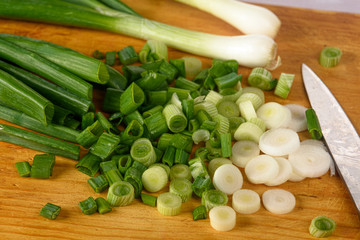 chopped green onions with a knife on the Board close-up