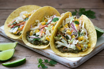 Vegetarian tacos stuffed with cabbage salad on a wooden background. Rustic style.