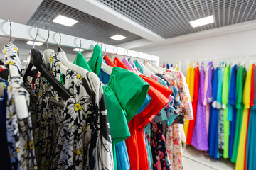 Fototapeta premium Cocktail dress. Clothing on hanger at the modern shop boutique. Bright multi-colored fabrics. concept of shopping.