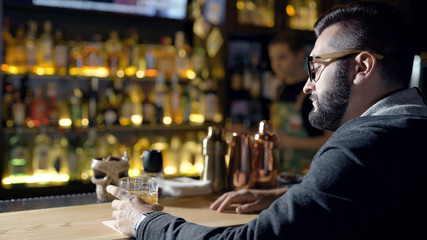 Man with glass of drink on bar counter