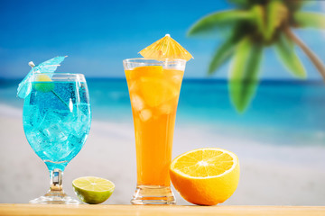 Glasses of fresh drinks decorated with olive umbrella and sliced lime orange