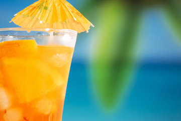 Glass of fresh orange drink decorated with bright umbrella