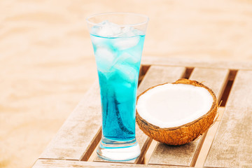 Glass of fresh blue drink and cracked coconut at wooden table