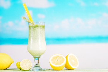 Glass of fresh lime smoothie and sliced citrus