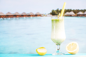Glass of tropical green smoothie and sliced citrus