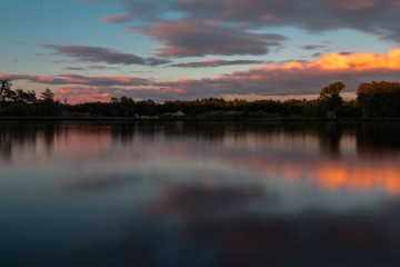 A long exposure of a colorful sunset with reflections at the cycling path through the water in Bokrijk in Belgium