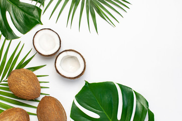 Fototapeta na wymiar Tropical leaves and fresh coconut on light gray background. Flat lay, top view, copy space. Summer background, nature. Healthy cooking. Creative healthy food concept, half of coconut