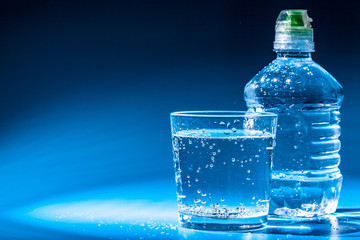 Glass of water with a bottle on table