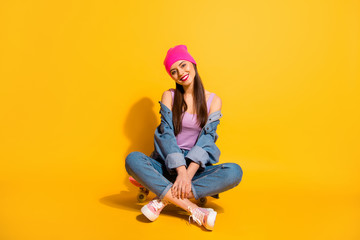 Full length body size photo beautiful she her lady rest relax vacation hobby sporty free time sitting own skate board wear casual jeans denim jacket shoes pink hat isolated yellow vivid background