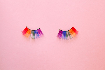 female colorful rainbow LGBT eyelashes isolated on pink background, copy space, top view