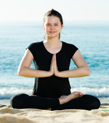 Fototapeta na wymiar Young girl in black T-shirt is sitting and sitting and doing yoga