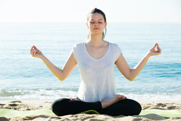 Portrait of sportswoman which is sitting and practicing asana in white T-shirt