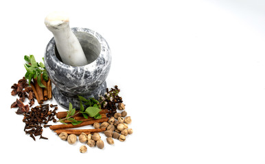 isolated dried spices such as cardamom clove cinnamon and nutmeg placed around marble mortar with...