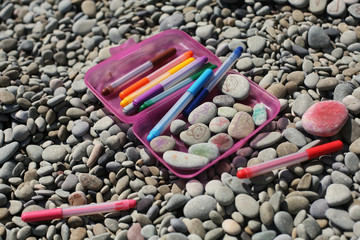 Close up of hand-painted colorful stones on a pebble beach on a summer morning. Kids activities. 