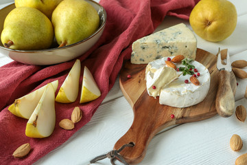 brie cheese, pears and almonds on a light wooden table