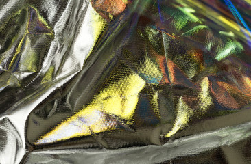 Textured silver foil background with shiny crumpled surface and gold reflects.