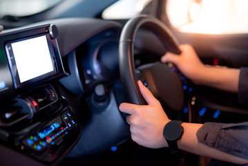 Male driver hand holding on steering wheel using digital dashboard monitor for GPS navigation on the car console in modern car. Urban driving lifestyle with automobile technology
