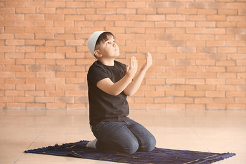 Little Muslim boy praying indoors