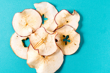 Dried apple chips over aqua background with copy space.