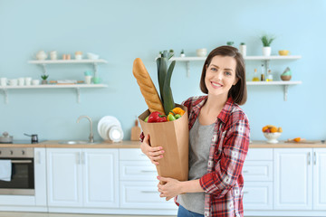 Young woman with bag full of products in kitchen